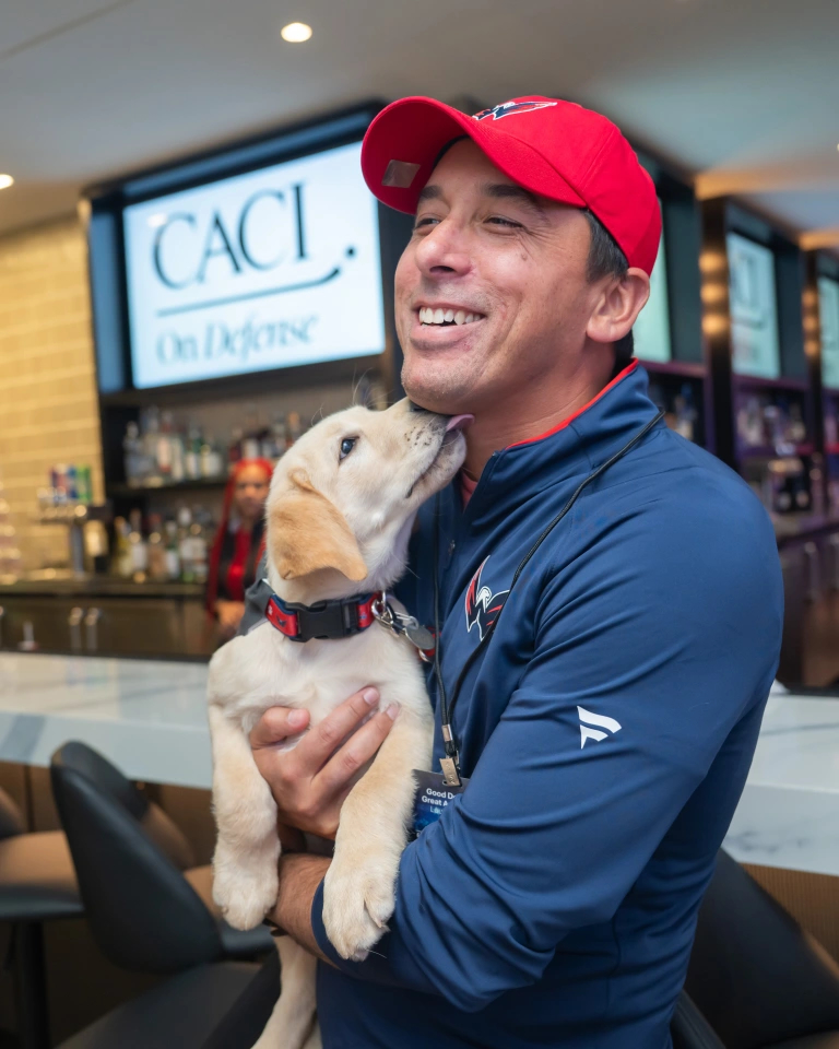 Vice President of Civilian Enterprise Solutions Kyle Fritts, gest a big kiss from Bravo, CACI’s first Good Dog.